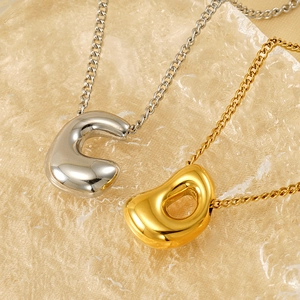 Polished gold and silver balloon bubble letter pendants on fluid textured surface