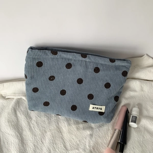 Detailed close-up of corduroy polka dot makeup bag on white fabric with beauty props