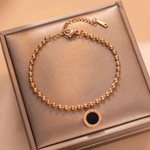 Rose gold beaded bracelet featuring a black enamel round pendant with Roman numerals