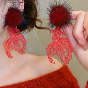 Detail view of festive red pompom and hollow goldfish earrings in New Chinese style