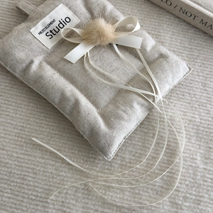 Detailed view of beige linen hair clip with white ribbon bow and soft pompom decor