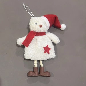 Detail of plush white Christmas bear ornament with red hat and star on beige backdrop