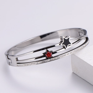 Detail of silver bangle featuring black and red star charms with rows of white zircons