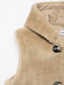 Detail of beige faux fur vest with black leather buckle and metallic clasp closure