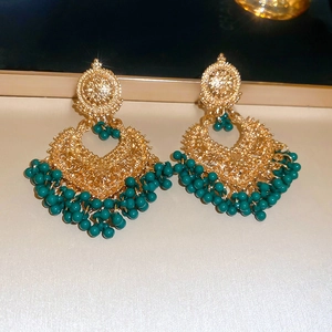 Detail of ethnic gold hollow teardrop earrings with green bead tassels and pearls