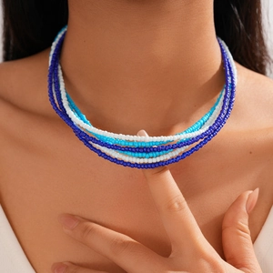 Detail of layered bohemian glass beaded necklace in blue and white beads on a model