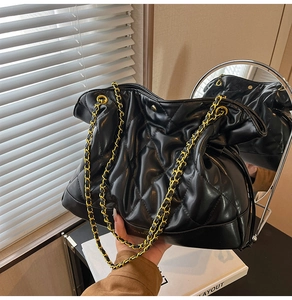 Detail of black quilted leather bucket bag with elegant golden chain strap and texture