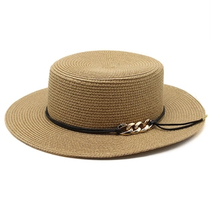 Détail d'un chapeau canotier en paille beige avec une chaîne dorée décorative