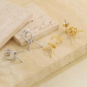 Detail shot of minimalist knot-shaped earrings in gold and silver finish on stone