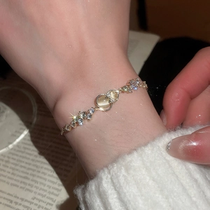 Close-up of gold flower bracelet with zircon hearts and sparkling cat-eye stones