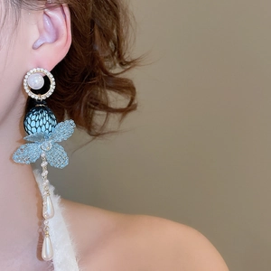 Close-up of light blue lace flower drop earrings with pearls and long metal tassels