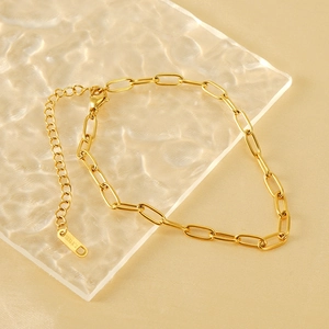 Close-up of golden paperclip chain with S.STEEL engraved tag and lobster clasp