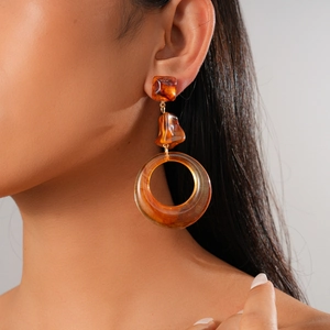 Macro detail of retro amber resin geometric hoop earrings worn by a model