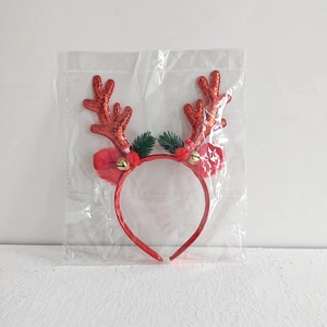 Close-up of Christmas headband with red glitter antlers, small gold bells and green pine needles