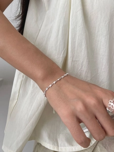 Detail showing S925 sterling silver star chain bracelet and floral hollow ring on wrist