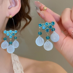 Detail of silver needle tassel earrings with blue zircon and teardrop shell charms