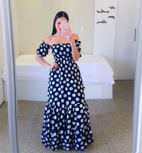 Close-up of a black off-shoulder polka dot maxi dress with tiered ruffle hem and puff sleeves