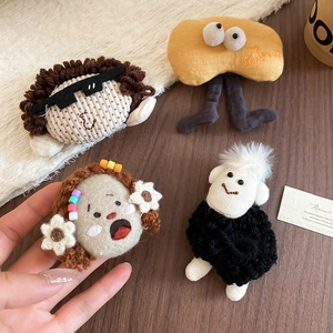 Detail showing four handmade plush character brooches with diverse textures and cute designs