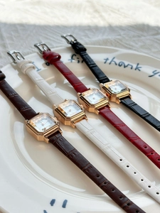 Detail view of four square leather strap watches on a ceramic plate for women