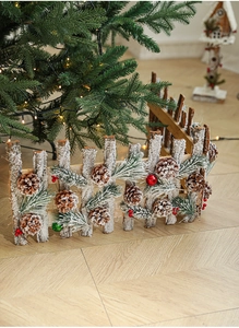 Detail of wooden Christmas fence with artificial snow, pine cones and colorful ornaments
