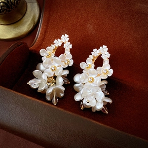 Macro detail of acrylic floral earrings with crystal center and water drop pendant