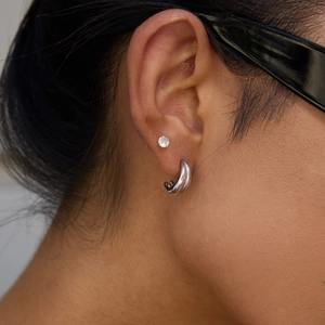 Detail view of 14K gold plated stainless steel C-shaped earring on model ear with silver stud