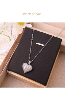 Detail shot of a silver heart pendant with pavé cubic zirconia on a black leather stand