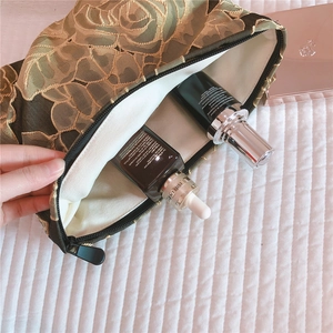 Olive green makeup bag with floral embroidery showing storage capacity for skincare