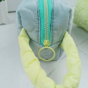 Detail of light blue quilted cosmetic bag with turquoise zipper and yellow handle