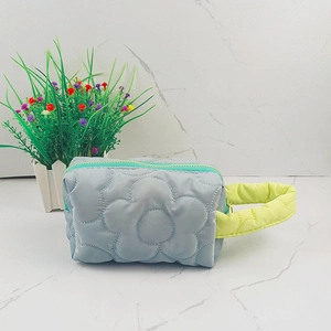 Macro detail of quilted blue makeup bag with large floral pattern and green zipper