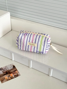 Quilted cotton toiletry bag with purple bow and stripe patterns on a desk