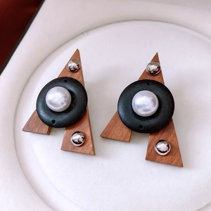 Detail of triangle wooden earrings featuring pearls and silver studs in retro ethnic style