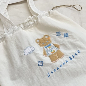 Detail of cute embroidered cartoon bear and stars on white drawstring canvas handbag