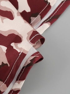 Close-up of double stitching on red-brown and beige camouflage satin fabric dress