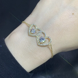 Detailed close-up of a gold heart bracelet with sparkling zircon stones on a female wrist