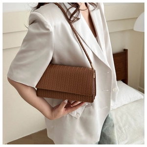Brown woven texture shoulder bag worn with a white blazer for a minimalist look