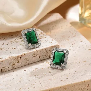 Emerald cut green zircon stud earrings with halo diamonds on beige stone and silk