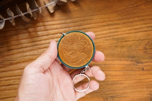 Close-up of vintage brown crazy horse leather mini tape measure with floral embossing