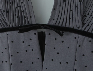 Detail of the V-neckline with flocking polka dots and a black velvet bow on the dress