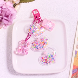 Close-up of pink glitter heart charms and gummy bear pendant with sweet candy tag