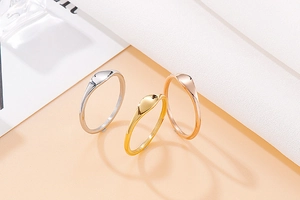 Minimalist titanium steel rings in silver, gold, and rose gold finishes on elegant background