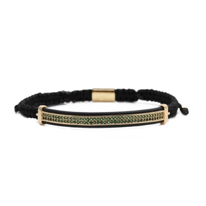 Macro detail of braided black rope bracelet with gold-plated metal green zircon stones