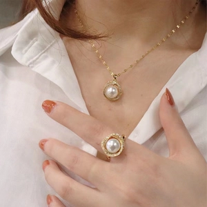 Elegant gold jewelry set featuring pearl necklace and matching ring on female model