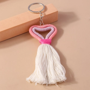 Detail of handmade knit heart keychain with soft pink and purple tones and cotton tassels