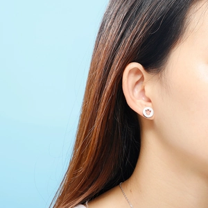 Silver round stud earrings with cutout angel design shown on model with light blue background