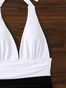 Dettaglio del costume da bagno a lupetto con scollo a V, top bianco a pieghe e fascia nera