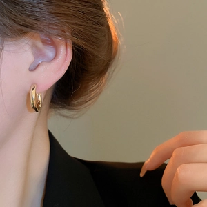 Close-up of polished gold round hoop earring worn on a model for a minimal look