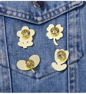 Lot de quatre broches fleurs dorées fixées sur le col d'une veste en jean