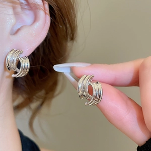 Detail of silver twisted geometric stud earrings featuring vertical textured stripes
