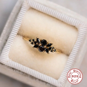 Macro shot of 925 silver gold-plated ring with black opal stones in a velvet box